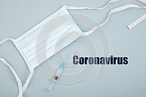 Coronavirus 2019-nCoV text on clipboard, disposable medical mask, personal protective equipment, syringe filled medicine or