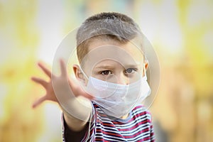 A Coronavirus and air pollution PM2.5 concept. European little boy wearing mask for protect pm2.5 and shows stop hand gesture to