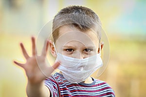 A Coronavirus and air pollution PM2.5 concept. European little boy wearing mask for protect pm2.5 and shows stop hand gesture to