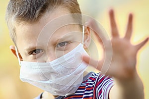 A Coronavirus and air pollution PM2.5 concept. European little boy wearing mask for protect pm2.5 and shows stop hand gesture to