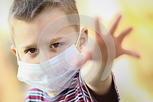 A Coronavirus and air pollution PM2.5 concept. European little boy wearing mask for protect pm2.5 and shows stop hand gesture to