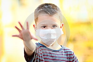 a Coronavirus and air pollution PM2.5 concept. European little boy wearing mask for protect pm2.5 and shows stop hand gesture to