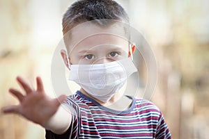 a Coronavirus and air pollution PM2.5 concept. European little boy wearing mask for protect pm2.5 and shows stop hand gesture to