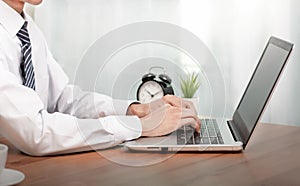 Coronavirus.Business man working on laptop computer  at home while sitting the wooden table.Male hands typing on the notebook