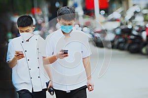 Coronavirus in China. Two young men in medical masks are walking down the street and holding phones. Epidemic of a new