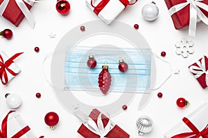 Coronavirus Christmas concept. Face mask in frame made of Christmas gift boxes and decorations on white background