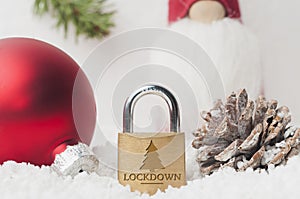 Coronavirus Christmas lockdown: a lock on the snow surrounded by christmas decorations and a Santa Claus puppy. Copy space