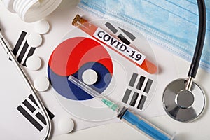 Coronavirus, the concept COVid-19. Top view protective breathing mask, stethoscope, syringe, pills on the flag of South Korea