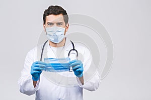 Coronavirus concept. Man Doctor Puts on Medical Mask Isolated over white background. Covid-19 flu pandemic