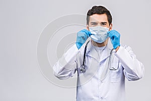 Coronavirus concept. Man Doctor Puts on Medical Mask Isolated over white background. Covid-19 flu pandemic