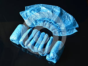 Coronavirus concept.Medical blue disposable shoe covers on black background.