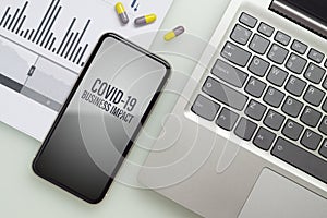 Coronavirus Covid-19 pandemic outbreak business impact background concept. Mockup mobile phone with laptop, business charts and