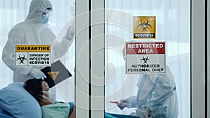 Coronavirus covid-19 quarantine and breakout alert sign on window of quarantine room at hospital with disease control experts try