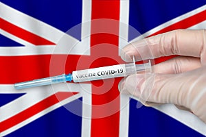 Coronavirus COVID-19 vaccination concept in United Kingdom of Great Britain and Northern Ireland with doctor hand and syringe