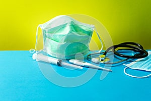 Coronavirus or Covid-19 Medical mask with Stethoscope,Electronic thermometer and syringe on blue table