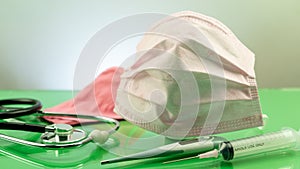 Coronavirus or Covid-19 Medical mask with Stethoscope,Electronic thermometer and syringe on green table