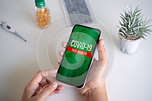 Coronavirus disease 2019 or Covid-19 test results online application background concept. Mockup mobile phone, a person holding
