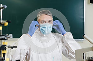 The coronavirus epidemic. A male doctor puts on a mask and looks at the camera. Close-up