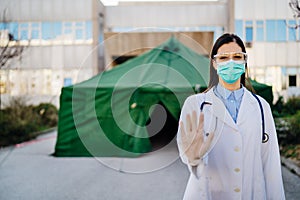 Coronavirus ER doctor in front of isolation hospital.Covid-19 physician with protective glasses / mask performing triage for virus photo