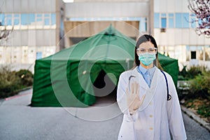 Coronavirus ER doctor in front of isolation hospital.Covid-19 physician with protective glasses / mask performing triage for virus photo