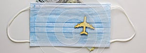 Coronavirus flight cancellations concept. Face mask and airplane toy on white background. Dollar bills. Copy space