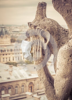 Coronavirus in France, surgical mask on gargoyle of Notre Dame in Paris