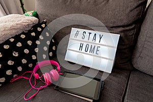 Coronavirus home lightbox sign with hashtag message  Stayhome glowing on home sofa with cozy. COVID-19 text to promote self