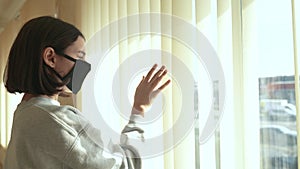 coronavirus. kid looks out window sad in a medical mask. stay at home. pandemic self-isolation coronavirus infection