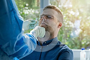 Coronavirus nasal swab test -  lab worker taking a mucus sample from male patient nose