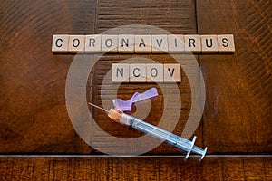 Coronavirus NCOV words made out of wooden tiles with a syringe photo