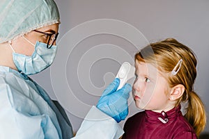 Coronavirus. Nurse or doctor checks girl`s body temperature using infrared forehead thermometer gun for virus symptom - epidemi