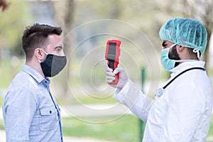 Coronavirus Nurse or Doctor Checks Man Body Temperature