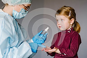 Coronavirus. Nurse or doctor in a protective suit, mask tells child how to use the sanitizer. Preventive measures against Covid-19