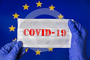 Coronavirus outbreak. Coronavirus update in Europe. Word Covid-19 on medical mask with flag of EU on background.