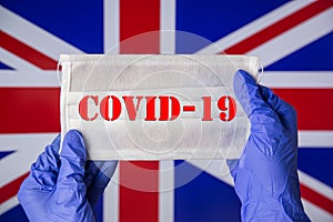 Coronavirus outbreak. Coronavirus update in Great Britain. Word Covid-19 on medical mask with UK flag on background.