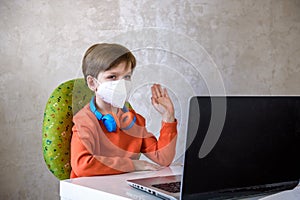 Coronavirus Outbreak. Lockdown and school closures. School boy with face mask watching online education classes feeling bored and