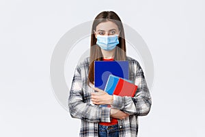 Coronavirus pandemic, covid-19 education, and back to school concept. Young female student in medical mask holding
