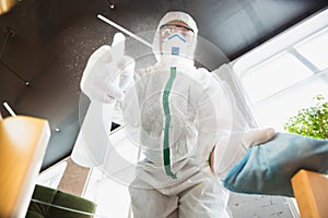 Coronavirus Pandemic. A disinfector in a protective suit and mask sprays disinfectants in the house or office