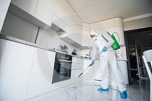 Coronavirus Pandemic. A disinfector in a protective suit and mask sprays disinfectants in house. Protection against COVID-19