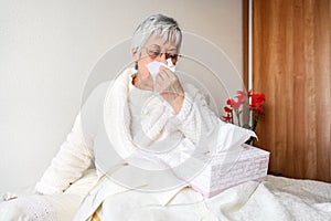 Coronavirus pandemic. Healthcare, flu, hygiene and people concept. Sick senior woman with paper wipe blowing his nose at