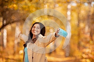 Coronavirus pandemic is over. Happy Caucasian woman taking off surgical mask at fall park, blank space. Selective focus