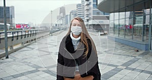 Coronavirus pandemic. Portrait of young blonde woman in face mask protection outside, street is empty during lockdown.
