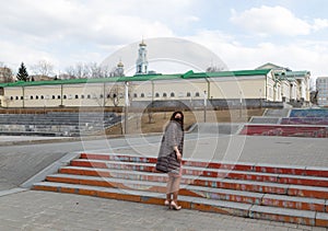 Coronavirus pandemic, a woman in a black mask walks down the stairs of an empty city`s historic quarter. Spring, cool weather,