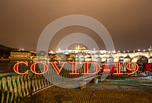Coronavirus in Prague, Czech Republic. Embankment of the Vltava River near Charles Bridge, night. Covid-19 sign