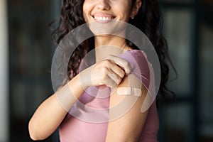 Coronavirus prevention. Unrecognizable female patient showing arm with band aid after corona vaccine injection at home