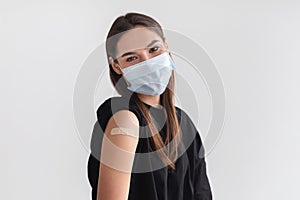 Coronavirus protection. Millennial Caucasian woman wearing face mask, showing arm after covid-19 vaccine injection