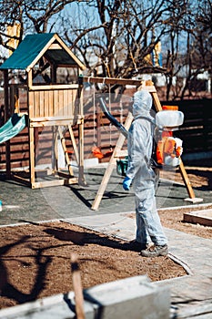 Coronavirus quarantine. Caucasian man wearing protective hazmat suit spraying disinfectant and chemicals