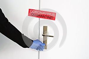 Coronavirus quarantine covid-19 red announcement on the sealed door, hand in blue rubber glove close entrance with key