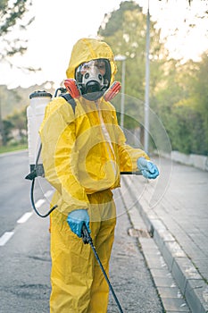 Coronavirus. A sanitation worker wearing a mask and cleaning the streets. Sterilize urban decontaminate city. Disinfecting against photo