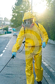 Coronavirus. A sanitation worker wearing a mask and cleaning the streets. Sterilize urban decontaminate city. Disinfecting against photo